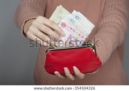 Chinese woman holding Yuan banknotes the official currency of mainland China with a red purse