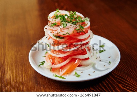 Uzbek national salad of tomatoes, onions, herbs and spices, chopped tomatoes and sliced onions stacked alternately, sprinkle with herbs and spices, vegetables