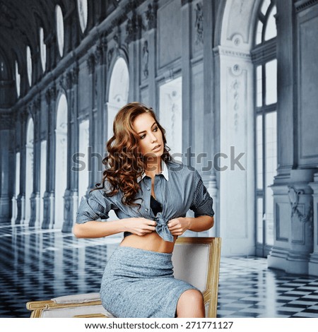 Beautiful girl in a striped shirt and tight skirt, black bra, curly hair, waist, hip, playful face, on a background of elegant background as a palace with columns, large windows and chic interiors