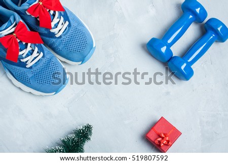 Christmas sport flat lay composition with shoes, dumbbells, christmas tree and red gift \
box on gray concrete background. Concept CÂ�hristmas special for healthy lifestyle and \
sport.