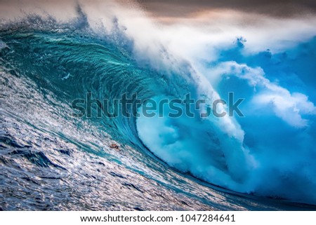 A huge wave crashing at sunset during a large swell