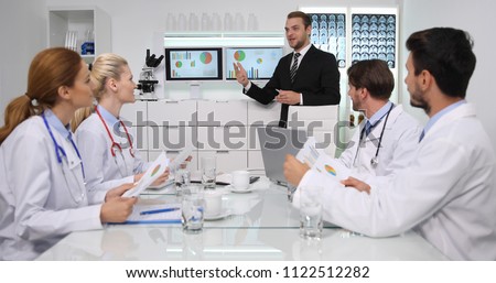 Happy Manager Man Positive Talking with Medical Doctors Team About Pie Chart Data in Hospital Cabinet or Healthcare Center Room
