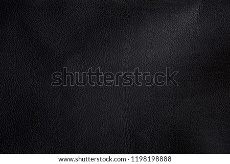 Photo of black leather texture with light irregularities for material background.