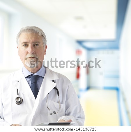 Doctor in the hallway of the hospital with tablet in hand.