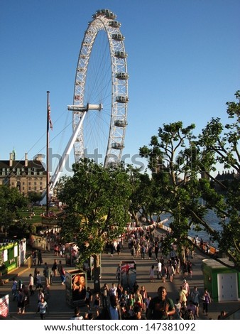 LONDON, UK - JUNE 26: People visit attractions by Thames river on sunny day on June 26, 2011 in London, UK. The London Eye is the most popular paid tourist attraction in the UK.