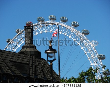 LONDON, UK - JUNE 26: View of black roof, street lamp, britain flag and famous London Eye on June 26, 2011 in London, UK. The London Eye is the the most popular tourist attraction in the UK.