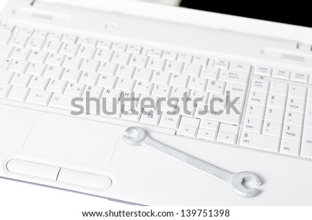 Laptop with a wrench on top symbolizing readiness for service / Laptop service