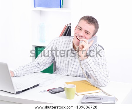 Young and handsome businessman in his office working and making telephone conversation