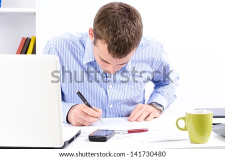 Young and handsome businessman in his office working and writing