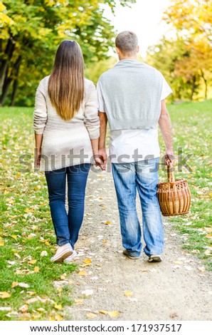 Happy young couple walking on a path and enjoying the autumn nature in the park