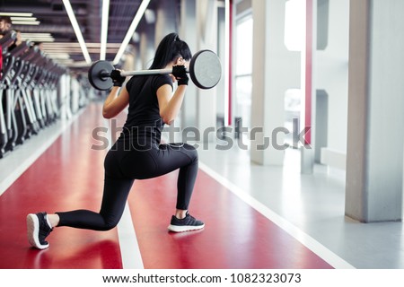 Attractive woman doing lunge exercise with barbell load on back