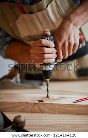 Carpenter drills a hole with an electrical drill, Wood boring drill in hand drilling hole in wooden block