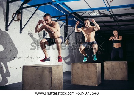 Fit young people doing box jumps as a group in a gym