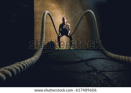 Young woman working out with battle ropes