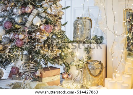 Christmas decorations. Decorated with elegant tree, candles, fireplace, gifts under the Christmas tree, Christmas balls, snowflakes, flying a light fabric, garland, lights.