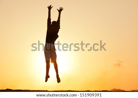 Silhouette of a young male at sunset jumping