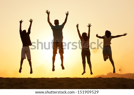 Family of four silhouette by a sunset jumping for joy