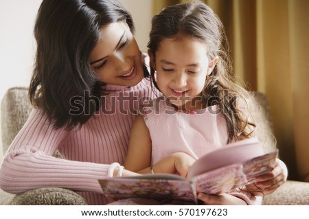 mother reads story book to her daughter