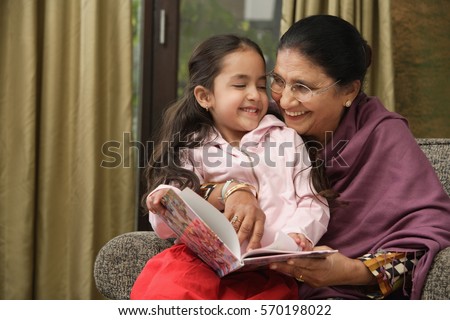 granddaughter sits on grandmother\'s lap for story (horizontal)