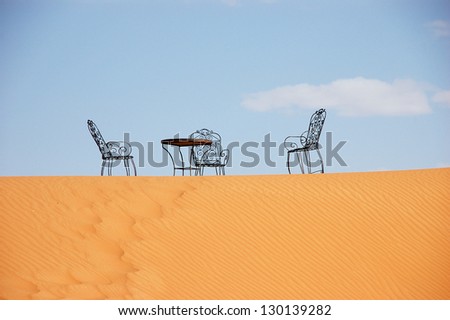 Wrought iron table and chairs on the top of sand dune of Erg Chebbi in the Sahara Desert, Morocco