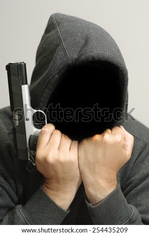 Hooded criminal with gun thinks about this next crime.