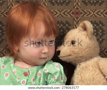 Vintage teddy bear whispers secrets to a toddler.