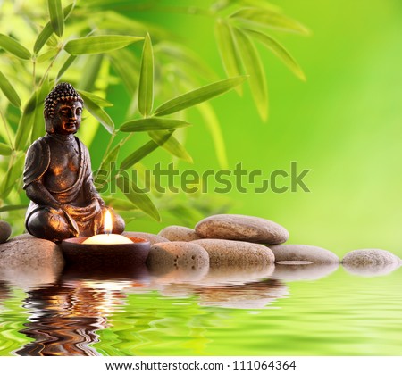 Buddha in meditation with burning candle,bamboo leaf and zen stones.