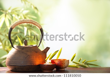 stock photo : Teapot and cups on table with bamboo leaves.