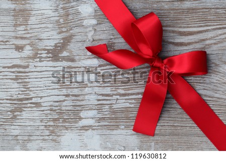 Red ribbon bow on wooden board with copy space