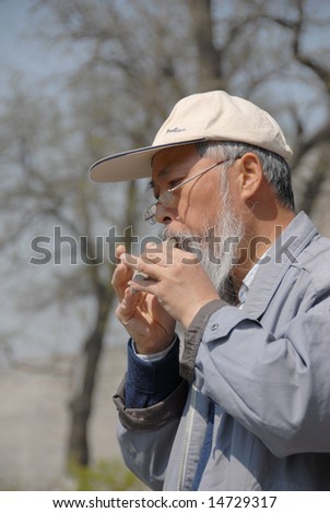 BEIJING - APRIL 12: an old man was performing a kind of Chinese ancient musical instrument in Ming rampart park of Beijing.