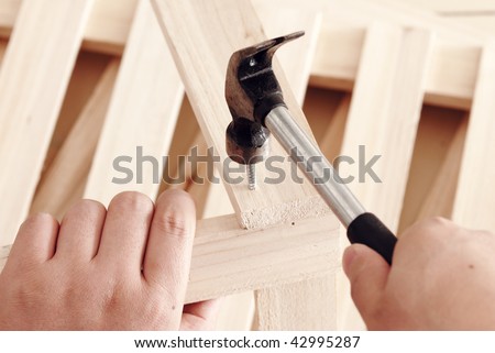 male hands driving nail with hammer, building works.