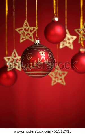Closeup of gold star and christms bauble on red  background.