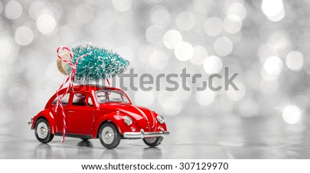 Miniature red car with fir tree on abstract background