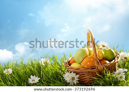 Basket of easter eggs on green grass at sunny day.
