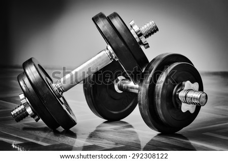 Black gym dumbbell with disks, black and white photo