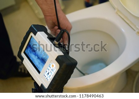 Checking clogged toilet pipe with inspection camera.