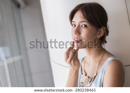 Beauty woman putting lipstick on the face. Portrait of Asia