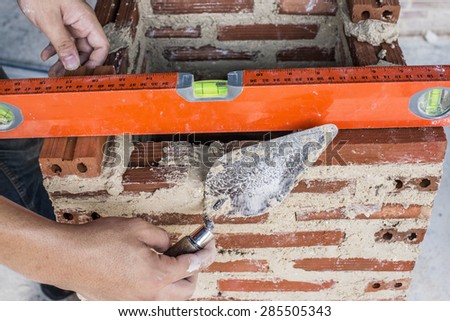 Trowel , Used and dirty spirit level above a rough unfinished concrete wall