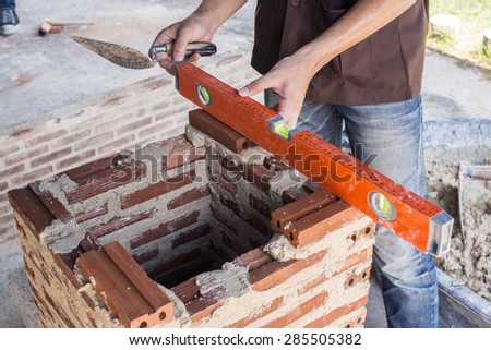 Craftsman measuring a brick wall with a spirit level