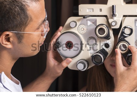 Ophthalmologist changing settings in eye test machine. Focus on doctor.