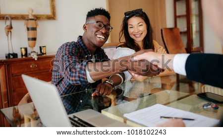 Happy property owners shaking hands with real estate broker after a deal. Young couple handshaking real estate agent after signing contract.