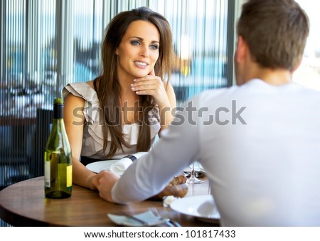 Portrait of a gorgeous woman holding hands with her boyfriend at a fancy restaurant