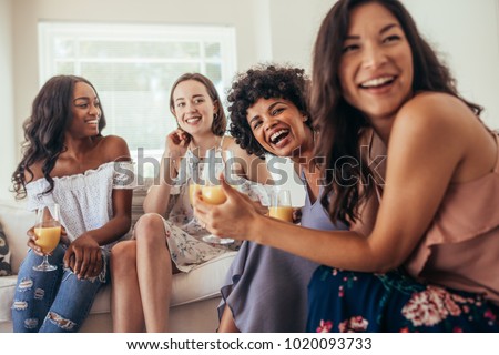 Diverse group of female friends enjoying at a party and laughing. Women friends having a party at home and looking away.