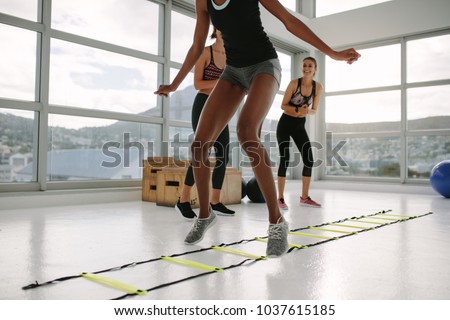 Woman training on agility ladder in gym. Fitness class cardio workout with speed ladder no floor.