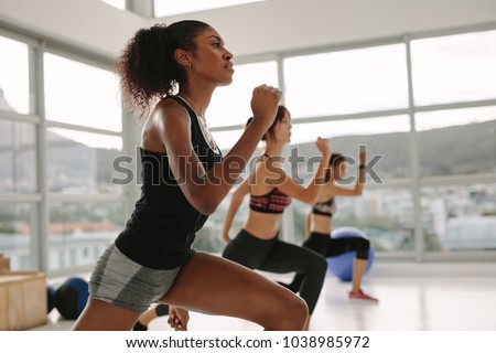Young woman in sportswear doing exercise during intensive circuit training in gym class. Females working out together in the health studio.