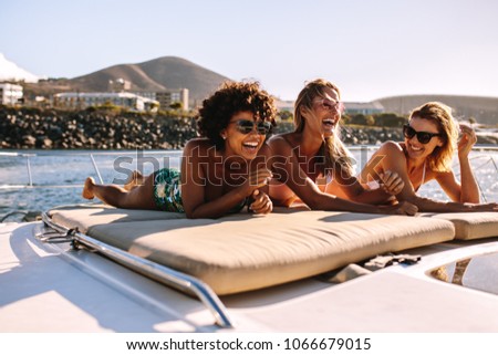 Beautiful young women relaxing on a private yacht deck in the sea. Three female friends sunbathing on luxury yacht and having a great time.