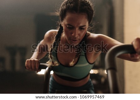 Woman doing intense workout on gym bike. Fitness female using air bike for cardio workout at gym.