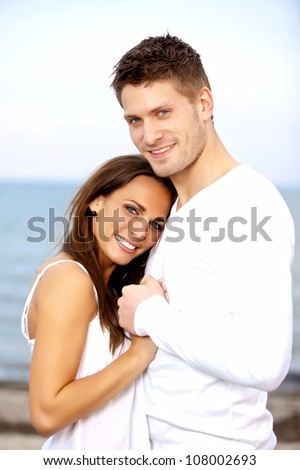 Portrait of a happy couple holding each other's hands posing with the sea as a background