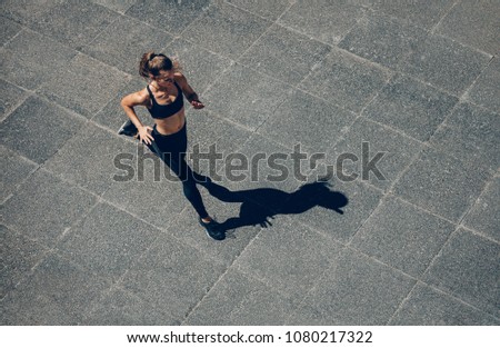 Woman sprinting in the morning outdoors. Top view of female runner working out in the city.