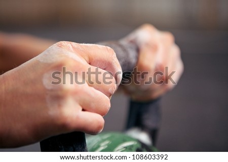 Closeup picture of two hands grabbing a kettle bell
